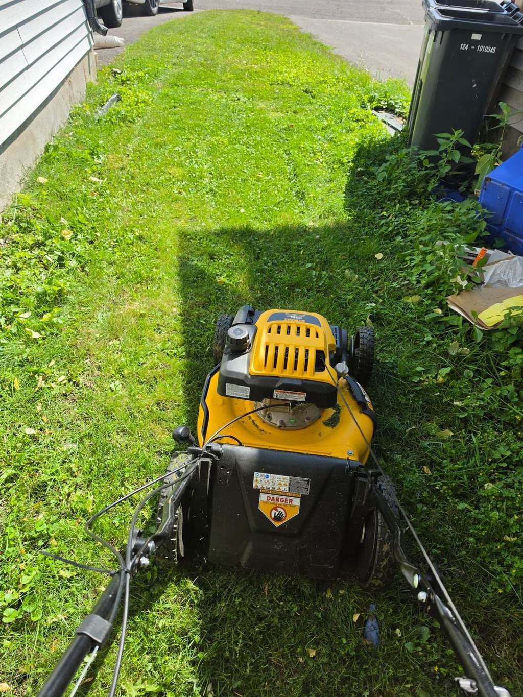 Mower cutting a narrow strip of lawn beside a house on an Ottawa residential property